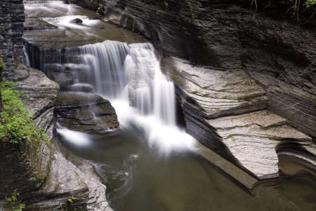 Beautiful waterfall in Enfield Glen which is part of  Robert Treman state park  New York. Lush green moss and ferns along the steep gorge walls add to the beauty of the scene. の写真素材