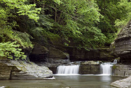 A small waterfall along Enfield Glen in Robert Treman state park in New York. Green spring colors along the stream add to the beauty of the scene. の写真素材
