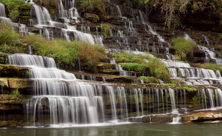 A amazingly beautiful series of cascades down a gorge wall. The water source is an underground cavern which pours the water out the side of the gorge wall. The wall is filled with beautiful ferns and vines and the water stair steps its way down the many lの写真素材