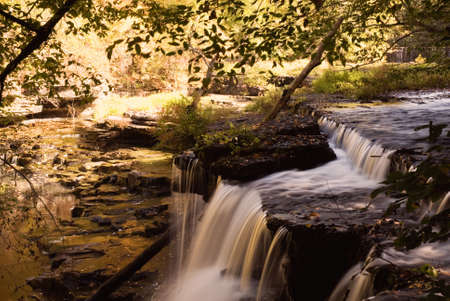 A small secluded waterfall in the forests of Tennessee. The setting sun made for some warm tones and nice colorful reflections in the water. の写真素材