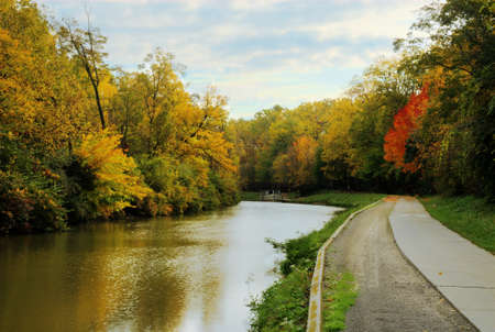Beautiful Autmn colors along the old Erie Canal in Toledo Ohio  A replica canal boat is scen in the distance  の写真素材