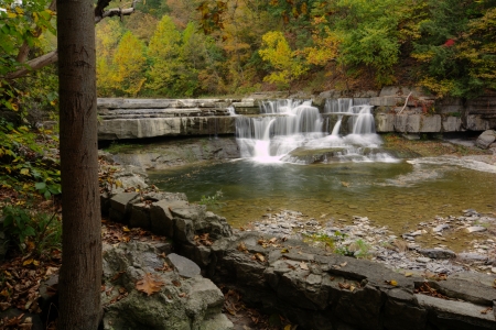 A small waterfall with colorful autumn foliage surrounding it. Seen along the Taughannock Falls gorge trail  in  Ulysses, New York. の写真素材