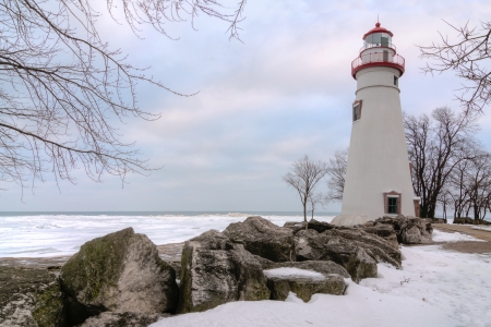The historic Marblehead Lighthouse in Northwest Ohio sits along the rocky shores of Lake Erie  Seen here in winter with snow on the ground の写真素材