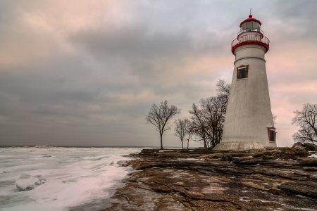 The historic Marblehead Lighthouse in Northwest Ohio sits along the rocky shores of Lake Erie  Seen here in winter with snow on the ground and ice on the lake の写真素材