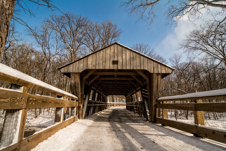 A snowy winter scene along a forest trail with a covered bridge crossing a creek. Found in Toledo...