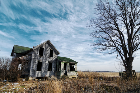 Photo of an old scary abandoned farm house that is deteriorating with time and neglect.  Enhanced...