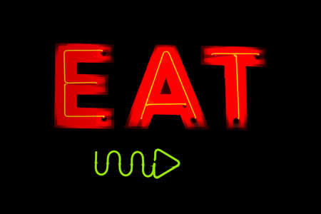 A neon sign with the word EAT and an arrow pointing the direction.の写真素材