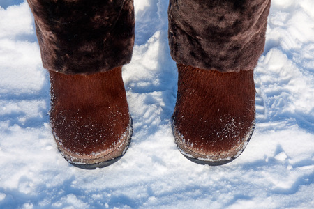 Big brown winter boots for women with a natural fur on the snowの写真素材