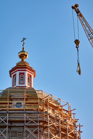 Reconstruction process of the orthodox cathedral using a crane and red bricks at golden hour under the sunlight, vertical imageの写真素材