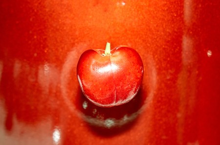 Single isolated cherry on the glossy red background, abstract food photographyの写真素材