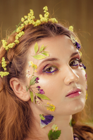 Woman with art fashion make up on face. Brown background.の写真素材