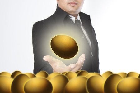 Businessman holding a golden eggsの写真素材