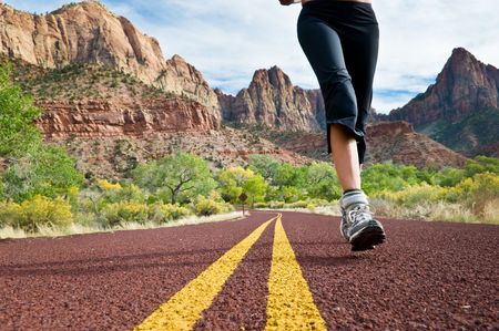 A woman running down a mountainous road.の写真素材