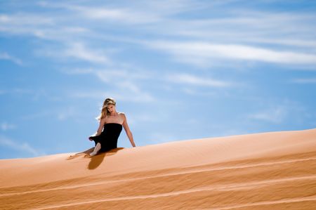 A beautiful woman in red dress walking on pink sand dunesの写真素材