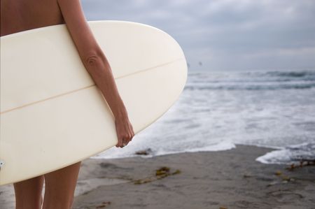 A woman surfer looking out at the ocean waves