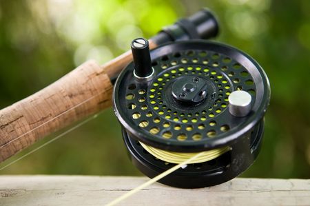 A fly reel and rod in a river setting.の写真素材