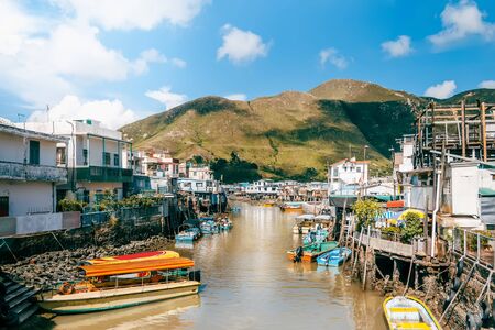 Traditional Asian Fishing Village and River under Blue Sky and Mountain in Hong Kong, Chinaの写真素材