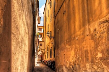 Traditional Narrow Italian Alley with Housing and Summer Sun in Florence, Italyの写真素材