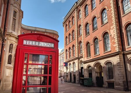 Iconic British Red Telephone Box in Street next to Red Brick Buildings, Nottingham, UK