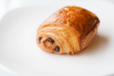 Freshly baked roll stuffed with chocolate on a white plateの写真素材