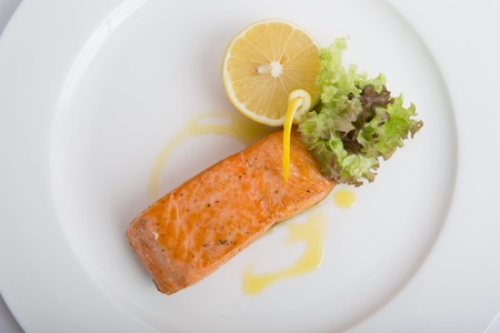 Salmon steak grilled and served with lemon and lettuceの写真素材