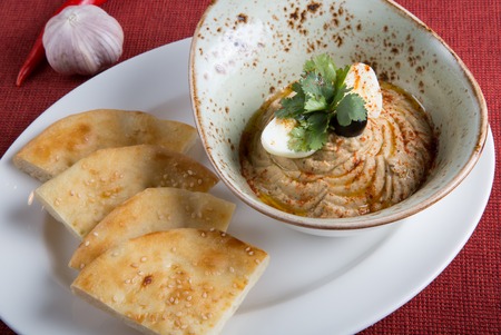Fresh hummus in a bowl with egg and parsleyの写真素材