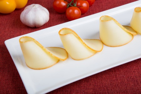 Yellow sliced cheese served on a white plateの写真素材