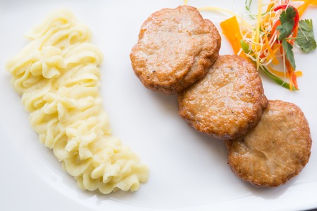 Meat cutlets with smashed potatoes on a white plateの写真素材