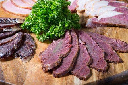 Different sorts of parma ham meat on wooden trayの写真素材