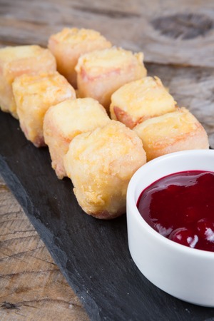 Fried cheese and bacon served on a wooden boardの写真素材