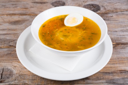 Russian soup with egg served in a bowl on a wooden tableの写真素材