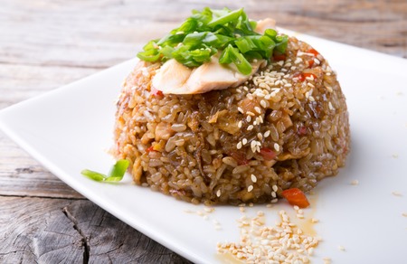 Fried asian rice with vegetable and meat served on a white plateの写真素材