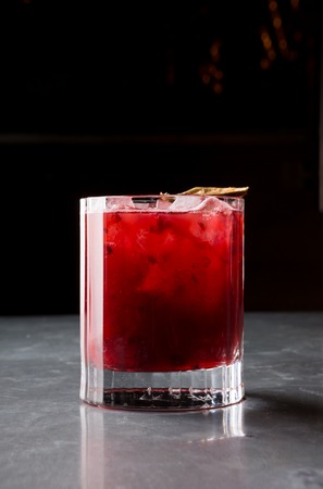 Red lemonade cocktail drink with ice at the bar