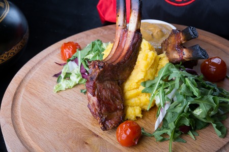 Grilled lamb meat served with salad on a wooden board