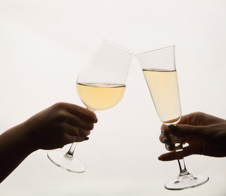 Women's hands cheering with wine glasses at the tableの写真素材