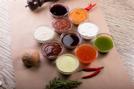 Different types of sauces background. Set of sauces - ketchup, mayonnaise, mustard, soy sauce, bbq sauce, pesto, mustard grains and pomegranate sauceの写真素材