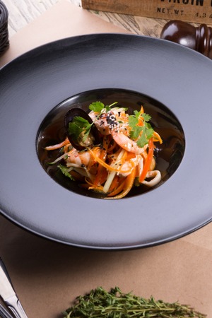 Asian seafood salad served on a black plateの写真素材