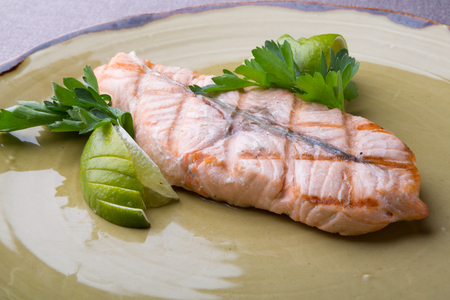 Steamed salmon steak served with lime on a rustic plateの写真素材