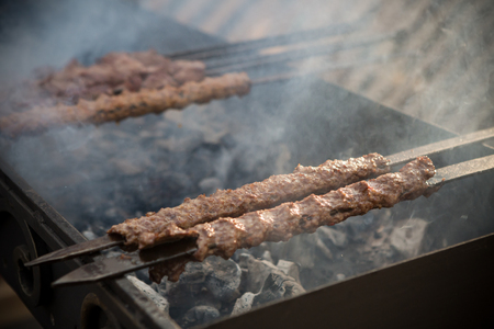 Meat being grilled on metal skewers outsideの写真素材
