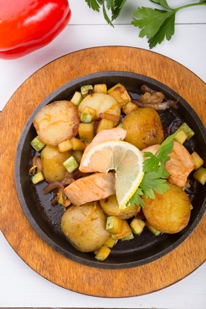 Fried salmon with potatoes on a sizzlerの写真素材