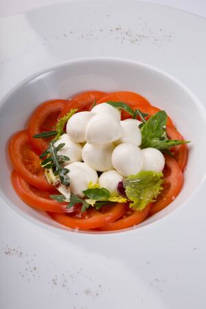 White buffalo mozzarella cheese with red tomatoes set on a tableの写真素材