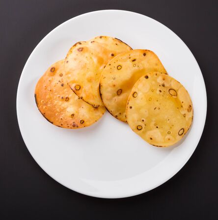 Yellow round potato chips on a whie plate