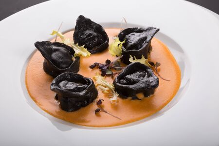 Black ravioli pasta with orange sauceの写真素材