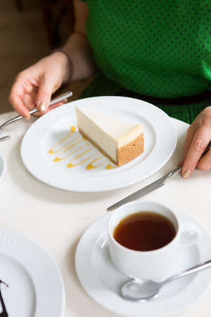 Woman eating cheese cake with cup of tea in a cafe