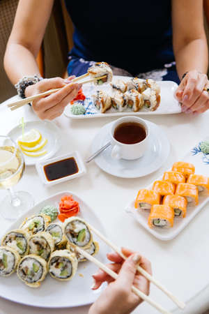 Two women eating japanese sushi rolls in a restaurantの写真素材