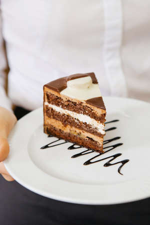 Waitress holding plate with slice of chocolate cake