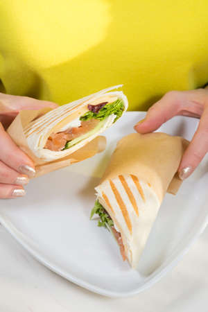 Woman holding freshly cooked salmon roll kebab