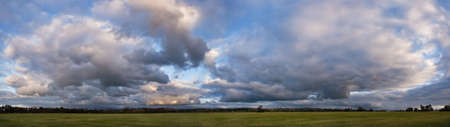 Sunset sky with painted clouds, farm field panoramic view