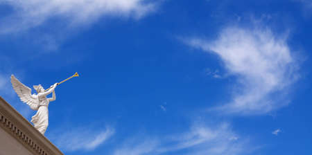 Angel with horn on blue sky background with white cloudsの写真素材