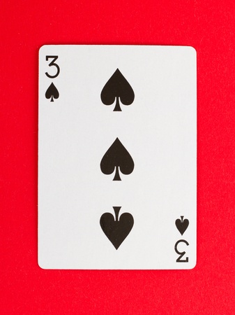 Playing card (three) isolated on a red backgroundのeditorial素材